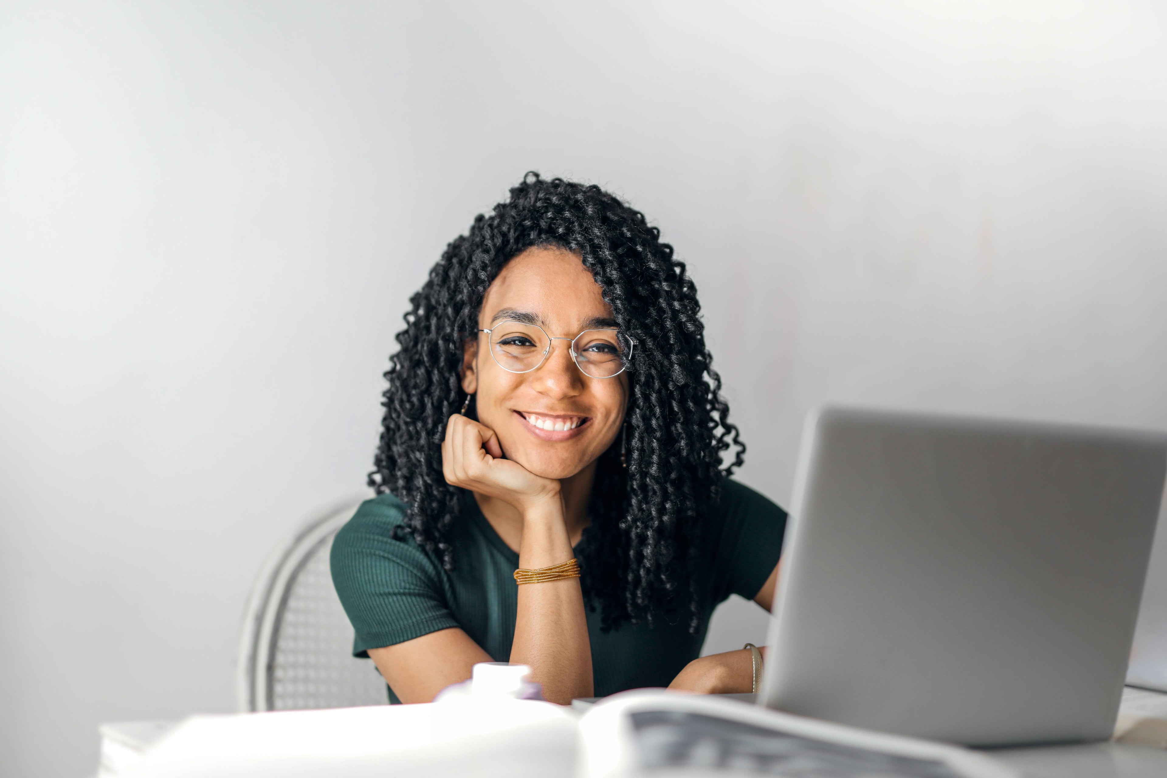 Young black woman sitting at her desk and excited to start a new role that pays her more and stressing her less. 